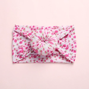 Detail of soft nylon baby headband with pink floral print and donut knot decoration