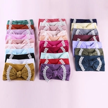 Flat lay of 18 colorful soft nylon baby headbands with large bows and lace details