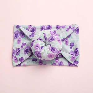 Close-up of soft purple floral print on grey baby headband with donut knot detail