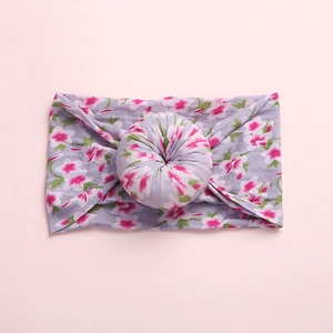 Detailed view of bohemian floral baby headband with a 3D donut knot on soft lilac fabric