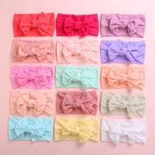 Flat lay of 15 colorful soft nylon baby headbands with large fluffy bows in a grid