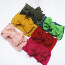 Flat lay of six colorful waffle knit baby headbands with large bows in varied hues