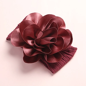 Detail of soft nylon dark red flower headband with layered petals and elastic knit fabric