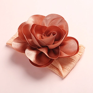 Close-up of soft nylon baby headband with a large bronze orange 3D rose flower detail