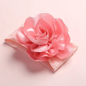 Détail d'un bandeau en nylon rose doux avec une grande fleur en satin pour bébés