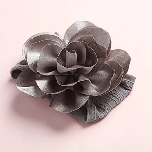 Detailed close-up of a soft grey nylon headband with a layered 3D fabric rose flower