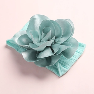 Détail macro du bandeau bébé en nylon souple avec une grande fleur en satin bleu clair