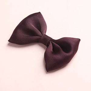 Detailed close-up of smooth satin fabric and symmetric texture on dark purple bow clip