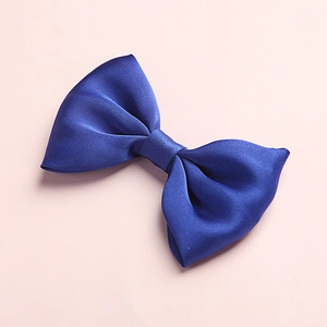 Close-up of a dark blue satin bow hair clip with a smooth texture on a pink background