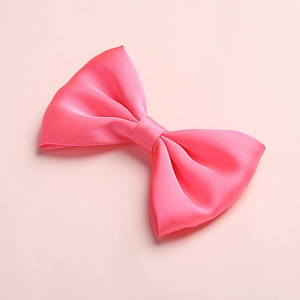 Detail shot of a pink satin bow hair clip with a smooth silky texture and fine stitching