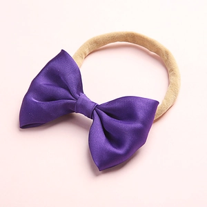 Detailed view of baby headband with a purple satin bow on soft elastic nylon band