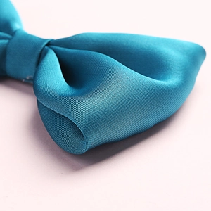 Detail shot of teal satin bow clip showing premium twill texture and silky luster finish