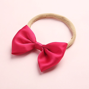 Detailed view of handmade rose red satin bow on elastic beige nylon baby headband