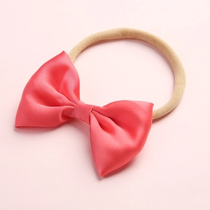 Detail of pink satin bow headband for infants with seamless nude nylon elastic band