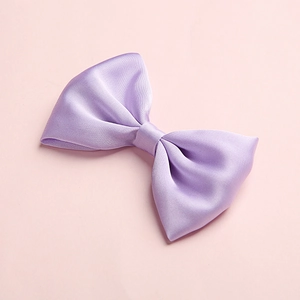 Detailed view of a purple satin bow clip with a smooth glossy finish on pink surface