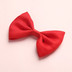 Close-up of a red satin ribbon hair bow with fine ribbed texture on a pink background