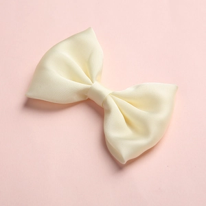 Detailed macro view of the cream satin silk texture on a girls double-wing bow hair clip