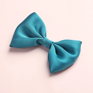 Detail showing the glossy turquoise satin fabric texture and double-layered bow design
