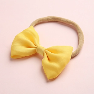 Detail of bright yellow bow hairband with soft high-elastic nylon strap for infants