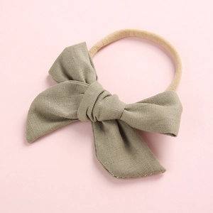 Detail of baby headband featuring soft sage green bow with cotton bamboo texture and nylon strap
