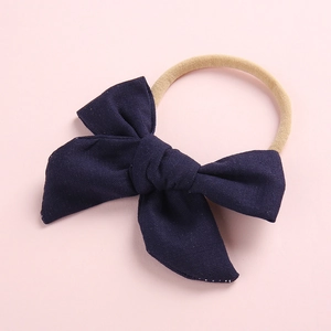 Detail of soft navy blue fabric bow headband with flexible nude elastic band for infants