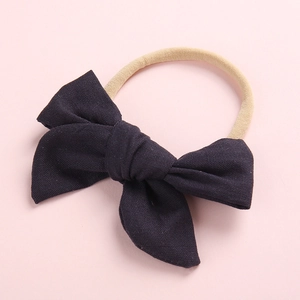 Detail of navy blue bamboo cotton bow on a soft nude nylon headband for infants
