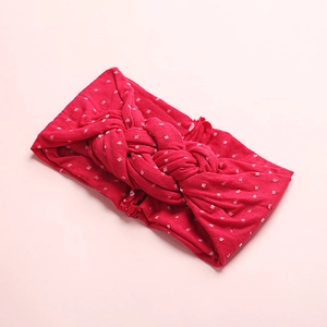 Détail d'un bandeau en nylon rouge à pois blancs avec un nœud tressé élégant