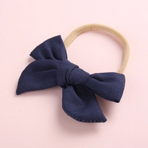 Detail of a dark blue cotton bow on a soft nude nylon headband for baby infants
