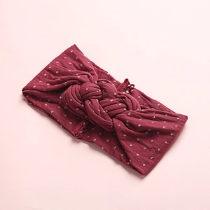 Détail macro du tissu en maille rouge vin avec pois blancs et design de nœud torsadé