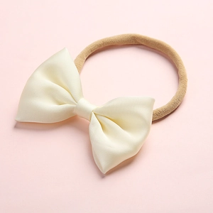 Detailed shot of cream satin bow on soft elastic nylon headband for babies