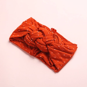 Gros plan d'un bandeau en nylon rouge à pois blancs avec un design à nœud torsadé