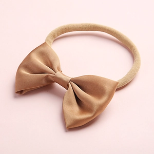 Detail of baby headband featuring a champagne satin bow with a soft elastic nylon band