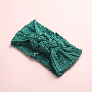 Détail du bandeau bébé vert foncé à pois blancs avec un grand nœud tressé élégant