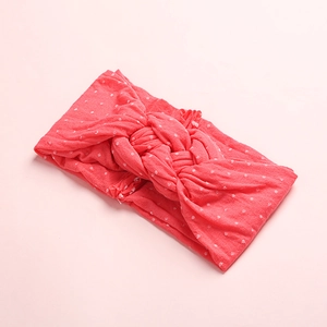Vue détaillée du bandeau en nylon corail à pois avec un nœud torsadé pour bébé