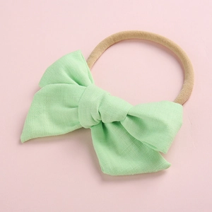 Detail of light green slub cotton bow on highly elastic nylon headband for babies