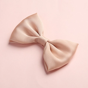 Detail showing the champagne satin texture and fine stitching of a children's bow hair clip