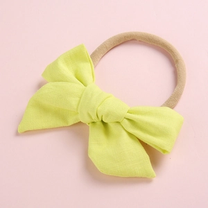 Detail of soft yellow cotton bow and nude high-elastic nylon headband for infants