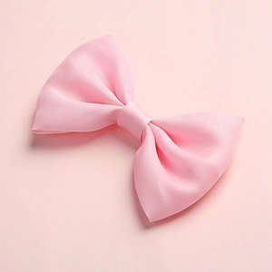 Close-up of pink satin bow hair clip showing detailed fabric texture and elegant craftsmanship