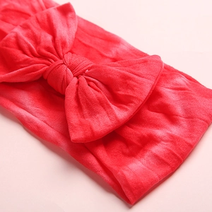 Close-up of coral red nylon baby headband with ribbed texture and large bow detail
