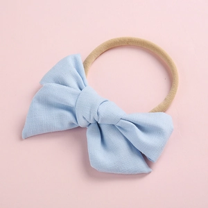 Close-up detail of soft light blue cotton baby headband with bow and elastic nylon band