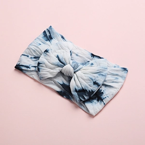 Detail view of blue and white marble tie-dye bow headband made of soft elastic fabric