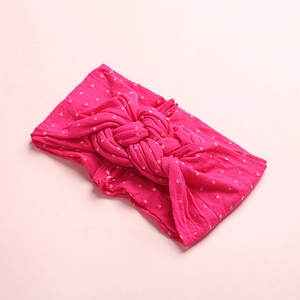 Vue détaillée du bandeau bébé en nylon fuchsia à pois blancs avec un nœud torsadé