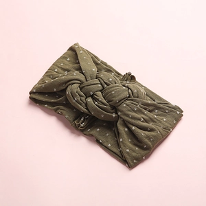 Détail du bandeau en nylon vert olive à pois blancs avec un nœud torsadé sur le dessus