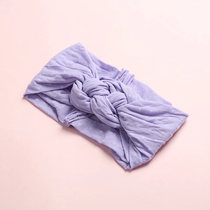 Détail d'un bandeau bébé en maille lavande avec pois blancs et nœud torsadé