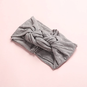 Détail d'un bandeau en nylon gris à pois avec un nœud torsadé et une texture en maille