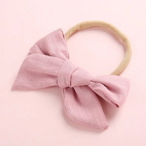 Close-up of pink cotton bow texture on a soft nude baby headband with clear fabric weave