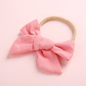 Detail of pink cotton bow on soft nylon headband for babies showing fabric texture