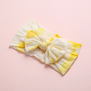 Macro shot of yellow tie-dye nylon baby headband with soft ribbed texture and bow
