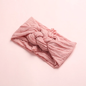 Détail d'un bandeau large noué rose à pois en tissu de maille doux et souple