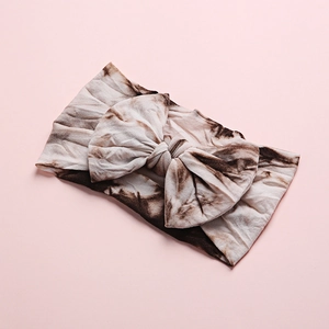 Close-up of brown tie-dye baby headband featuring a soft knit oversized bow design